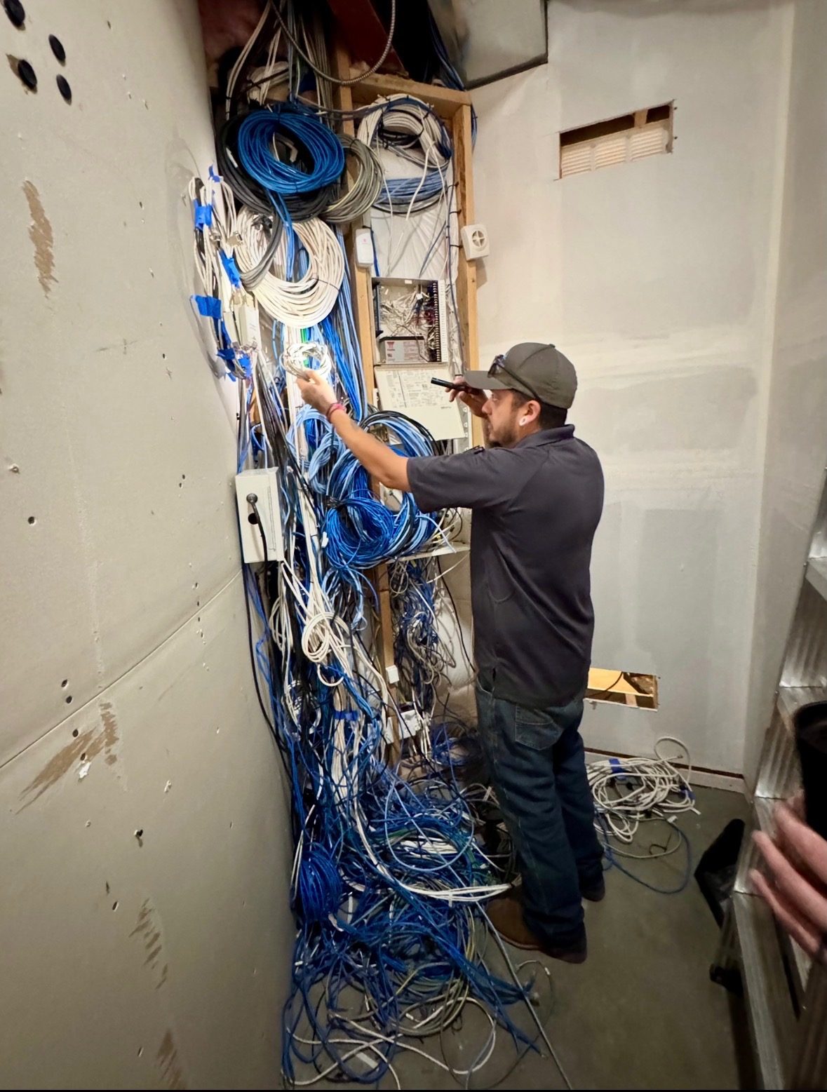 Technician with a flashlight working through a dense nest of legacy cabling
